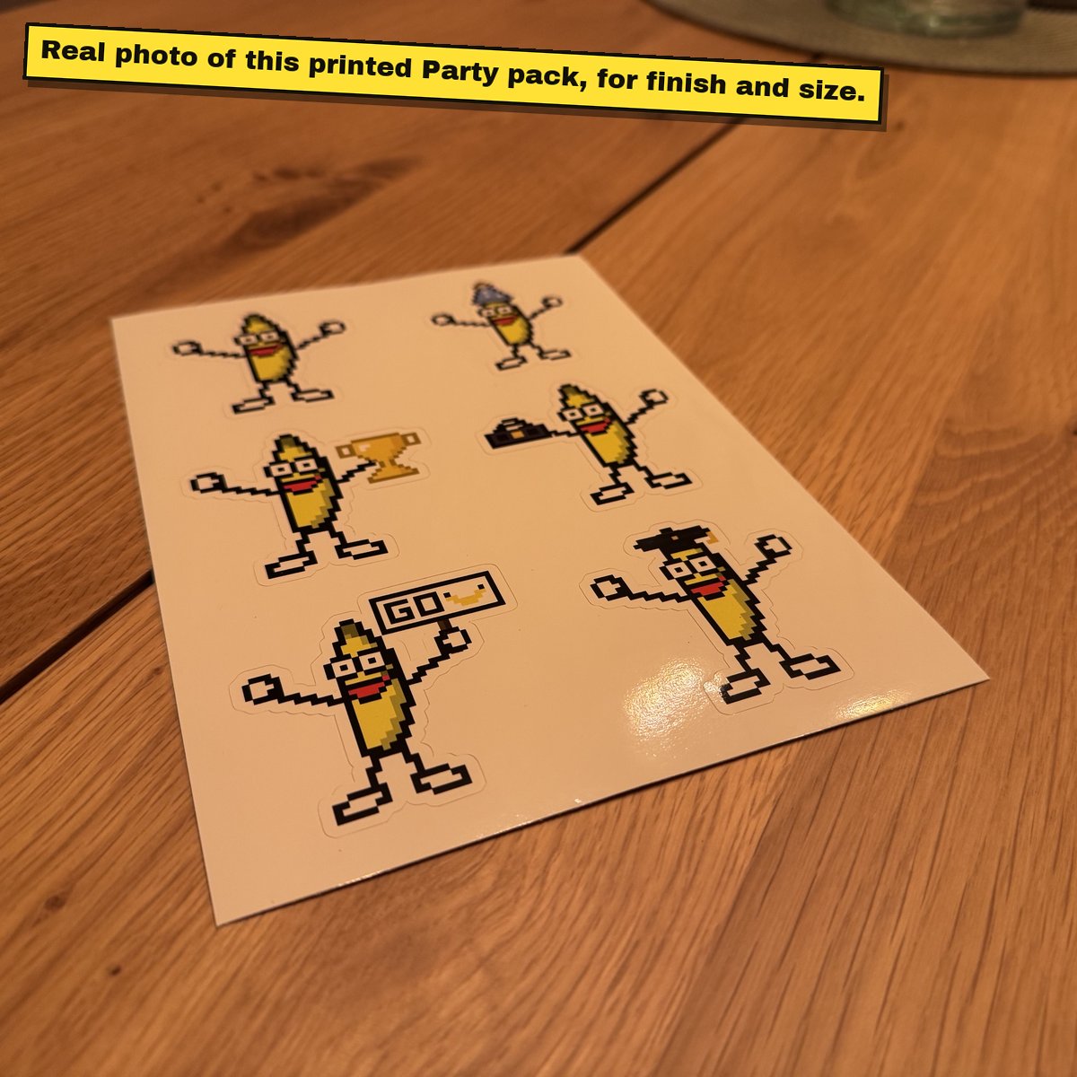 Printed A5 sticker sheet of pixel bananas on a wooden table.